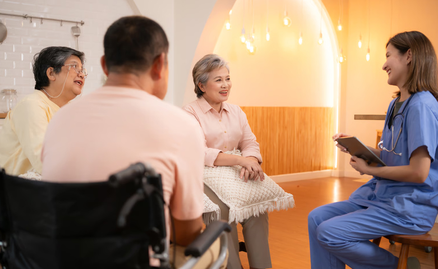 A hospice nurse holding a digital tablet consults with a patient and family during an initial hospice homecare assessment visit.
